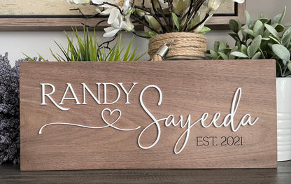 Wooden sign with 'RANDY Sayeeda EST. 2021' text, surrounded by plants.